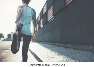 Woman athlete doing warming stretching in the city street. Tight sport clothes. Urban workout - Powered by Shutterstock