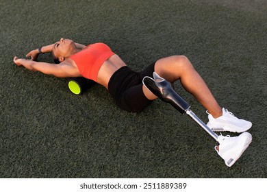 Woman athlete with prosthetic leg resting her back on a back roller - Powered by Shutterstock