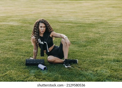 Woman athlete is sitting on a lawn near bluetuth speaker and mfr