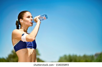 woman athlete takes a break,  she drinking water, out on a run on a hot day - Powered by Shutterstock