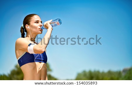 woman athlete takes a break,  she drinking water, out on a run on a hot day