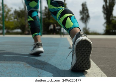 Woman with athletic legs in sneakers walks on street, close up - Powered by Shutterstock