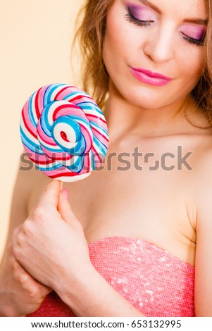 Woman attractive cheerful girl colorful make up holding big lollipop candy in hand. Sweet food and enjoying concept. Studio shot bright background