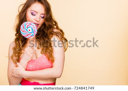 Woman attractive cheerful girl colorful make up holding big lollipop candy in hand. Sweet food and enjoying concept. Studio shot bright background