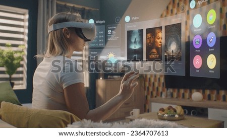 Woman in augmented reality headset chooses movie or TV show to watch at home. 3D graphics shows interface of streaming service app and widgets in user menu. VFX animation. Entertainment and lifestyle.