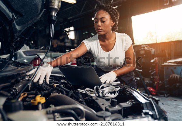 Woman auto\
mechanic using laptop for checking and repair maintenance auto\
engine is problems at car repair\
shop.