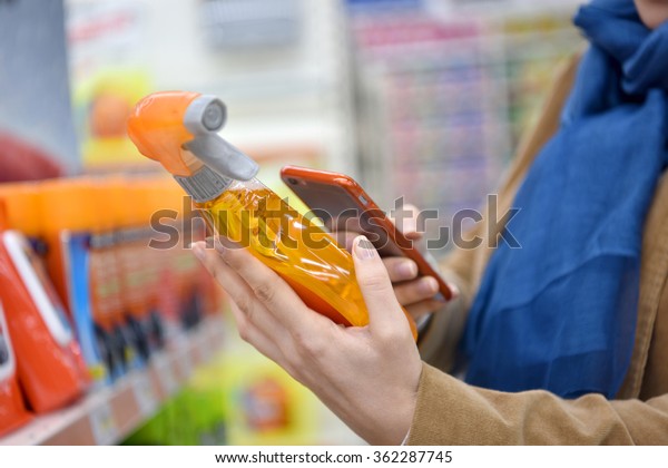 Woman in auto repair shop scanning products\
with smartphone