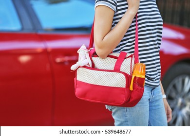 Woman With Baby Bag Standing Near A Car