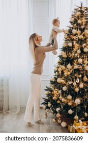 Woman with baby daughter decorating Christmas tree