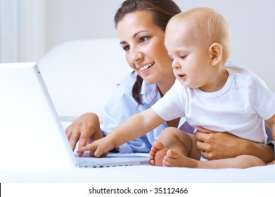 Woman With Baby And Laptop In Bed