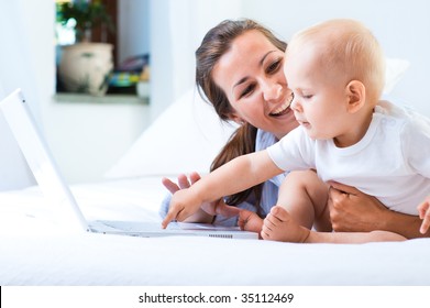 Woman With Baby And Laptop In Bed