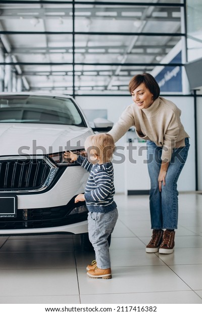 Woman with\
baby son choosing a car in a car\
salon