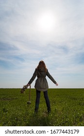 Woman Back To Camera Holding Gas Mask In Green Field On Clear Blue Sky Background And Breathing Fresh Air. Enviromental Protection, Ecology, Earth Saving, Pollution Prevention, COVID-19, Hope Concept.