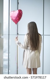 Woman With Back To Camera Holding Heart Shaped Balloon