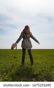 Woman Back To Camera Standing In Green Field On Clear Blue Sky Background Holding Gas Mask In Hand. Enviromental Protection, Ecology, Earth Saving, Pollution Prevention And Hope Concept. Copy Space.