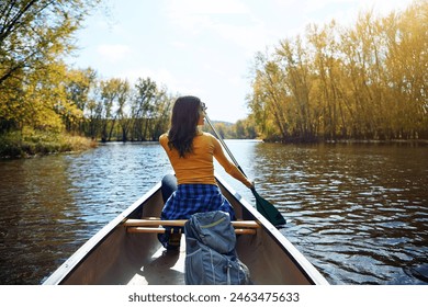 Woman, back and kayaking in nature on lake, wellness hobby and backpack for supplies with paddle for rowing. Vacation, relax and explore exercise on travel holiday, kayak boat and trees on riverbank - Powered by Shutterstock