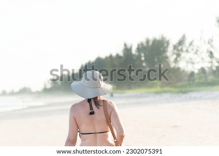 Woman from the back walking on the beach. Late afternoon. Guaibim, Valenca, Bahia.