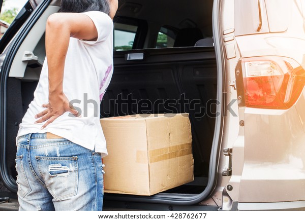 Woman with\
backache while lifting box in the\
car.