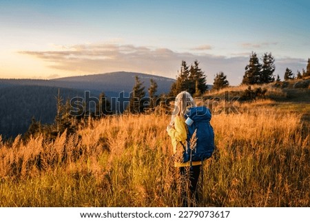 Woman with backpack looking at mountain range in natural parkland Jeseniky during sunset. Landscape with hiking tourist