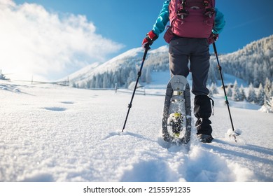 a woman with a backpack in snowshoes climbs a snowy mountain, winter trekking, hiking equipment - Shutterstock ID 2155591235