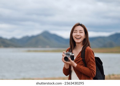 woman with a backpack standing over beautiful Mountain View, Traveler woman talking photo beautiful landscape of nature with vintage camera. - Powered by Shutterstock