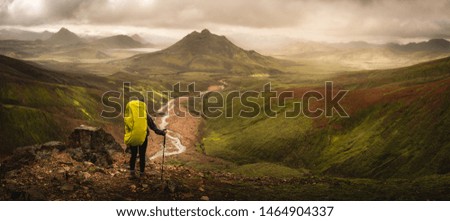 Woman backpacker hiking the Laugavegur trail looking at beautiful green panoramic mountain views