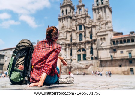 Woman backpacker piligrim siting on the Obradeiro square (plaza) in Santiago de Compostela