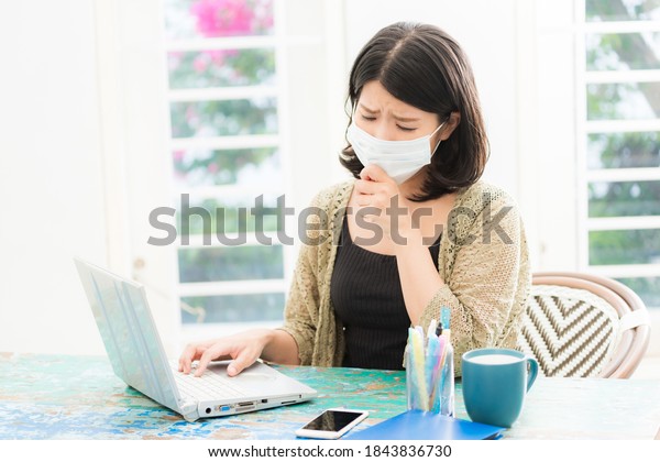 a woman with a bad physical condition\
wearing a mask sitting in front of a\
computer