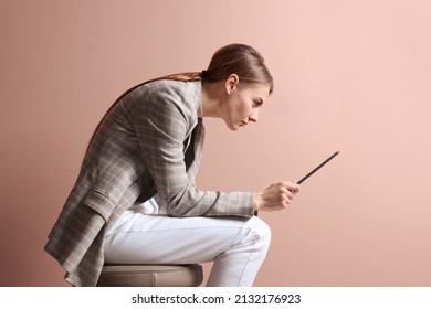 Woman with bad posture using tablet while sitting on stool against pale pink background - Shutterstock ID 2132176923