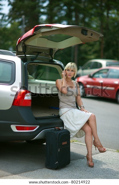 woman with baggage waiting at the car and talking\
to mobile phone