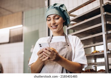 Woman Baker At The Pastry Store Having Break, Using Phone