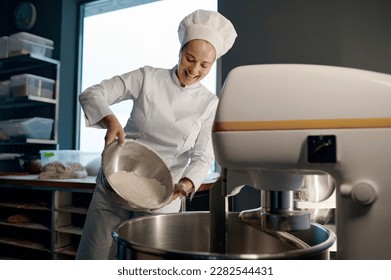 Woman baker pouring flour in mixing machine at bakery - Powered by Shutterstock