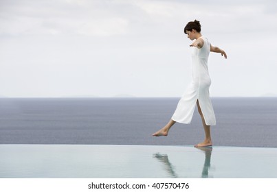 A Woman Balancing On The Edge Of A Pool