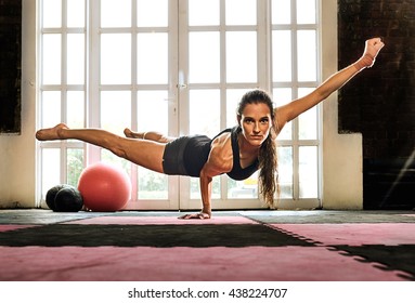 Woman Balancing While Doing A One Hand Push Up Showing Strength And Determination