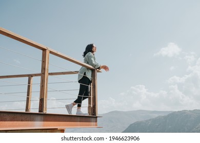 Woman in a balcony over a massive river and the mountains living the moment liberty and freedom concept, wellness during a sunny day
