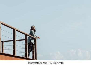 Woman in a balcony over a massive river and the mountains living the moment liberty and freedom concept, wellness during a sunny day