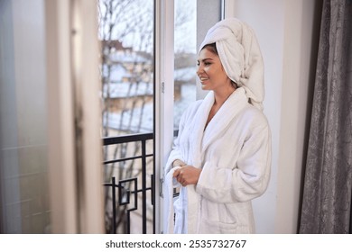 Woman balcony, White bathrobe, Towel wrap. Woman stands by balcony in white bathrobe and towel wrap, enjoying peaceful moment while looking outside at scenery. - Powered by Shutterstock