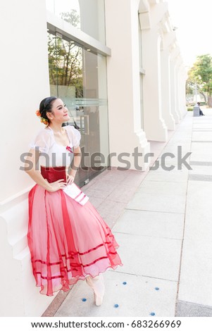 woman ballerina who has little smile and wear white and red romantic tutu costume stand with toes