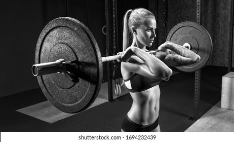 Woman with barbell Caucasian female performing deadlift exercise with barbell Confident woman crossfit workout in gym. Female performing deadlift exercise with weight bar Black and white photo.