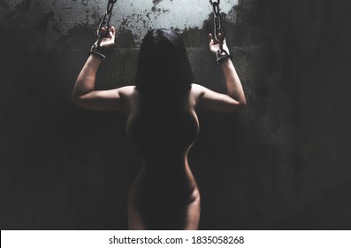 Woman bare body hands bondage with old rusty metal chain in the dark room, conceptual image sex abuse rape
