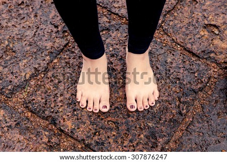 Woman bare feet on wet rocky pavement after rain