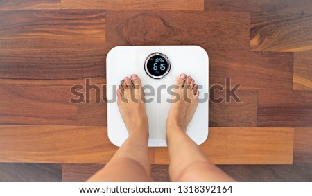 Woman bare feet standing on a digital scale with body fat analyzer that uses bioelectrical impedance (BIA) to gauge the amount of fat in your body