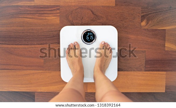 Woman bare feet standing on a digital scale\
with body fat analyzer that uses bioelectrical impedance (BIA) to\
gauge the amount of fat in your\
body