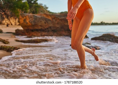 Woman With Bare Legs Running Along The Ocean Shore Cropped View                             