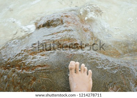 Woman barefoot standing on beach stone floor background.