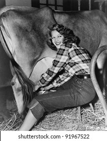 Woman In A Barn Milking A Cow