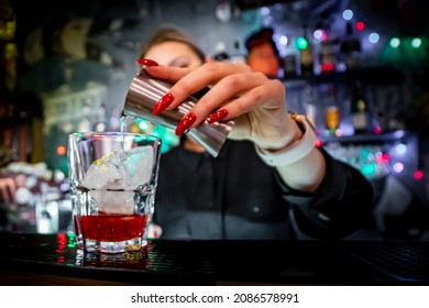 Woman Bartender Pours Alcohol Into A Glass With Ice At The Bar 