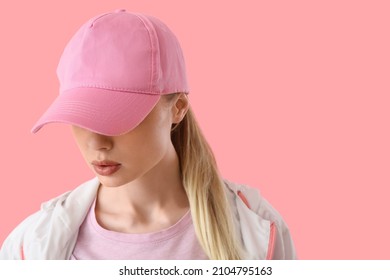Woman in baseball cap on pink background, closeup
