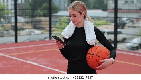 Woman with basketball ball and smartphone on basketball court. Using smartphone after training. Concept of sport, active lifestyle. - Powered by Shutterstock