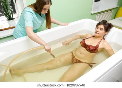 Woman in bath during hydromassage in beauty spa salon. Underwater hydrotherapy massage procedure